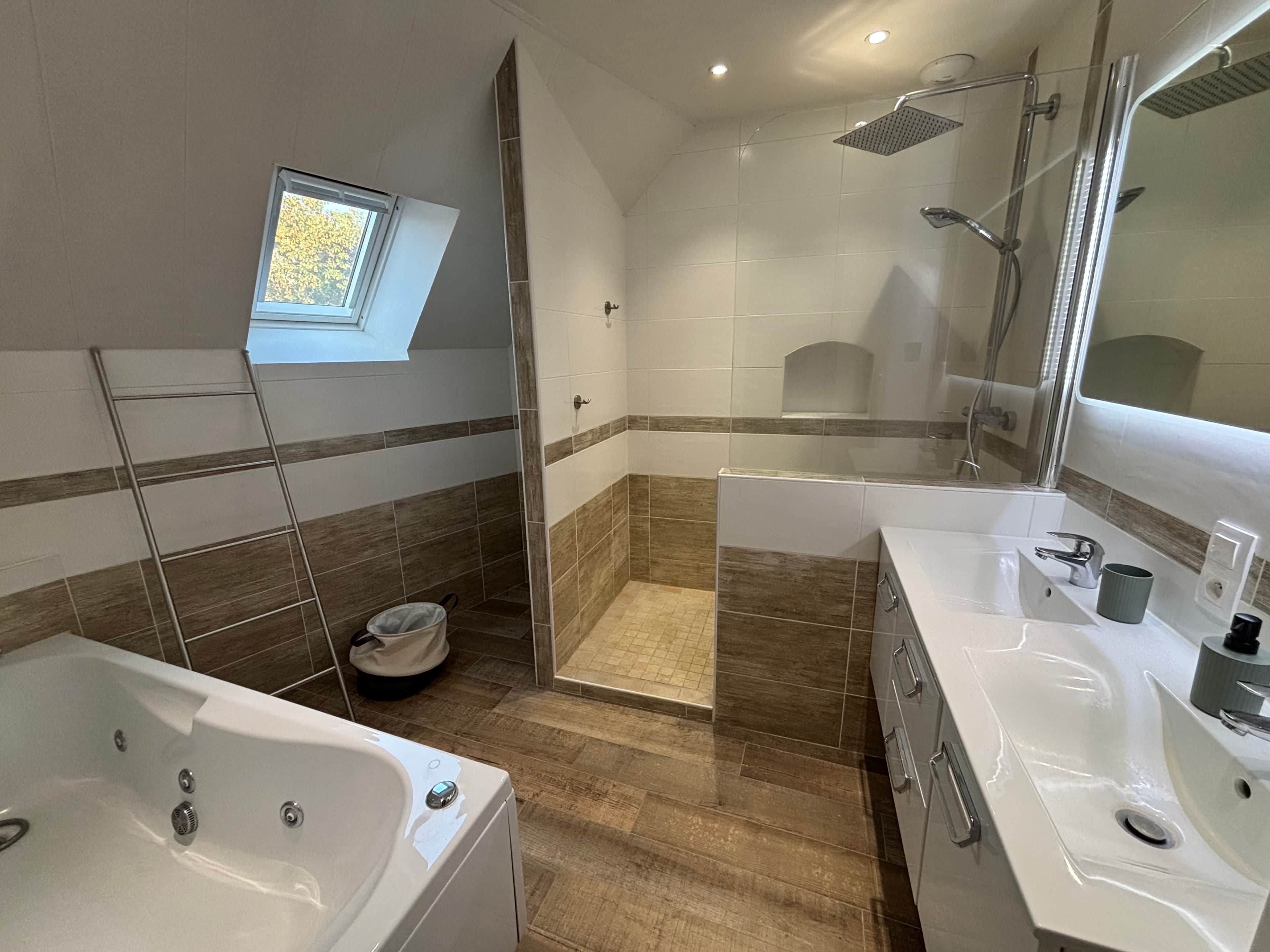 Un baño moderno con bañera, ducha y un ventanal pequeño.