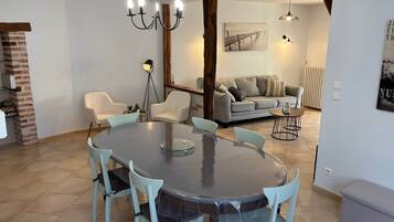 Un coin repas avec une table ronde et des chaises, un lustre et un canapé en arrière-plan.