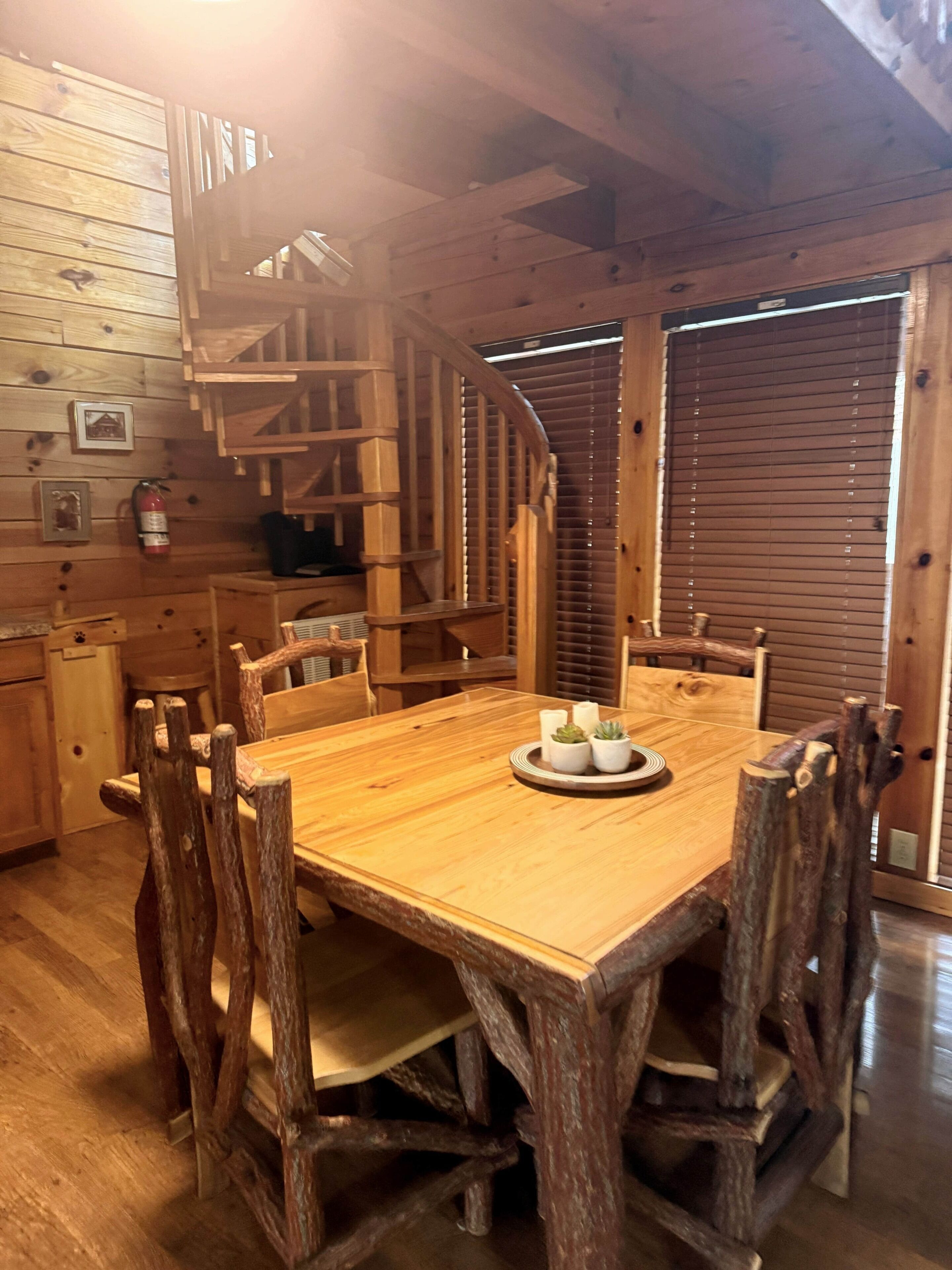 Un intérieur en bois comprenant une table à manger, des chaises et un escalier en colimaçon.