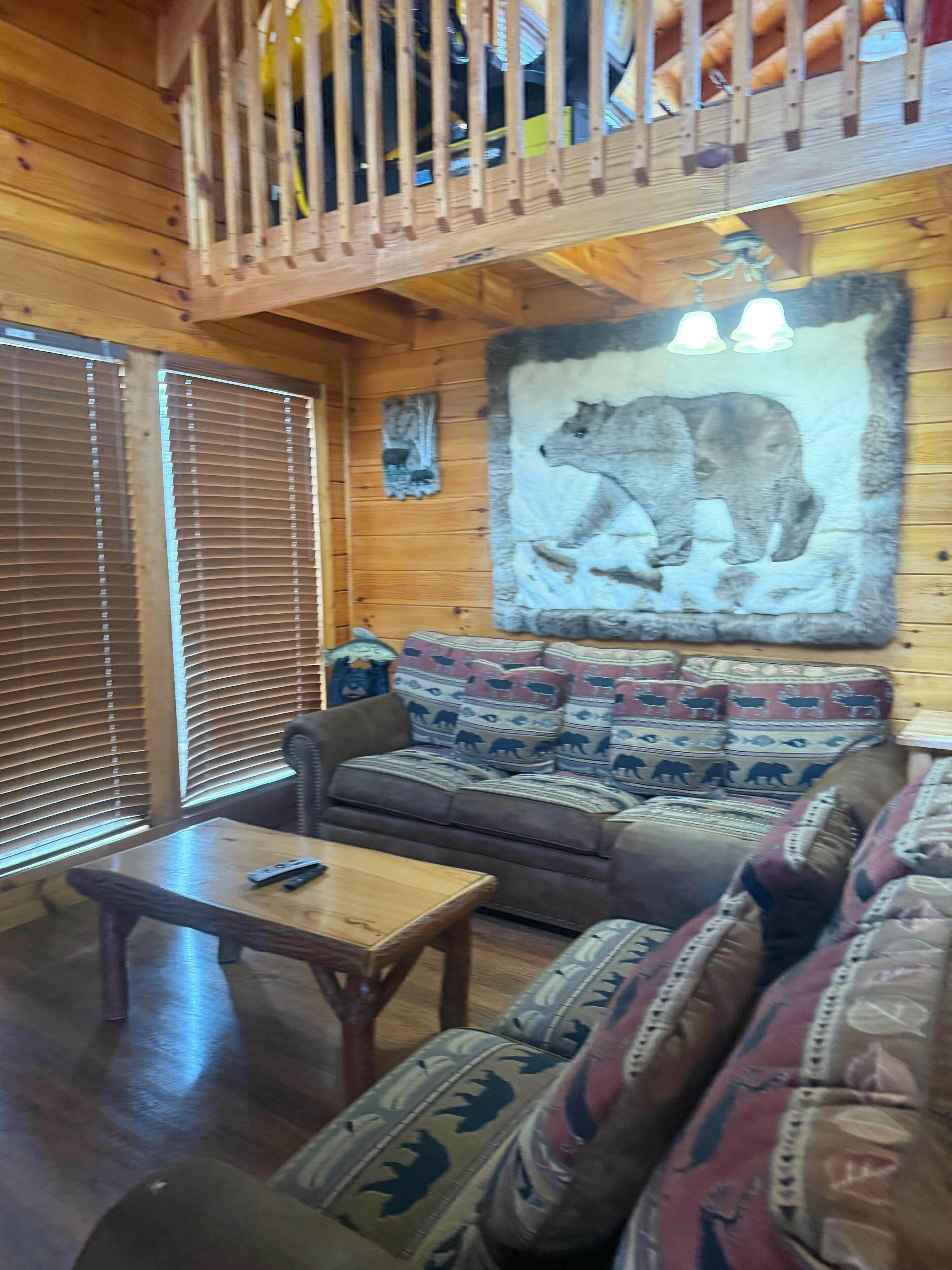 A wooden interior with a sofa, a table, and a large bear mural on the wall.