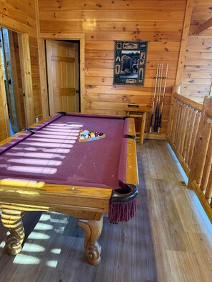 A pool table with a purple felt surface, surrounded by wooden walls and a wooden floor. - A Bear's Kind of Fun (Sevier County)