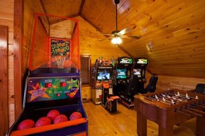 A room with a basketball hoop, a foosball table, and arcade games. - Bear's Bliss Luxury Cabin with Pool & Theater (Sevier County)