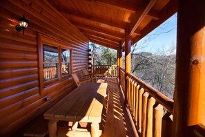 Una baita di legno con portico coperto, panche in legno e ringhiera.