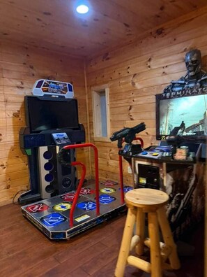 A wooden room with a gaming console, a television, and a statue.