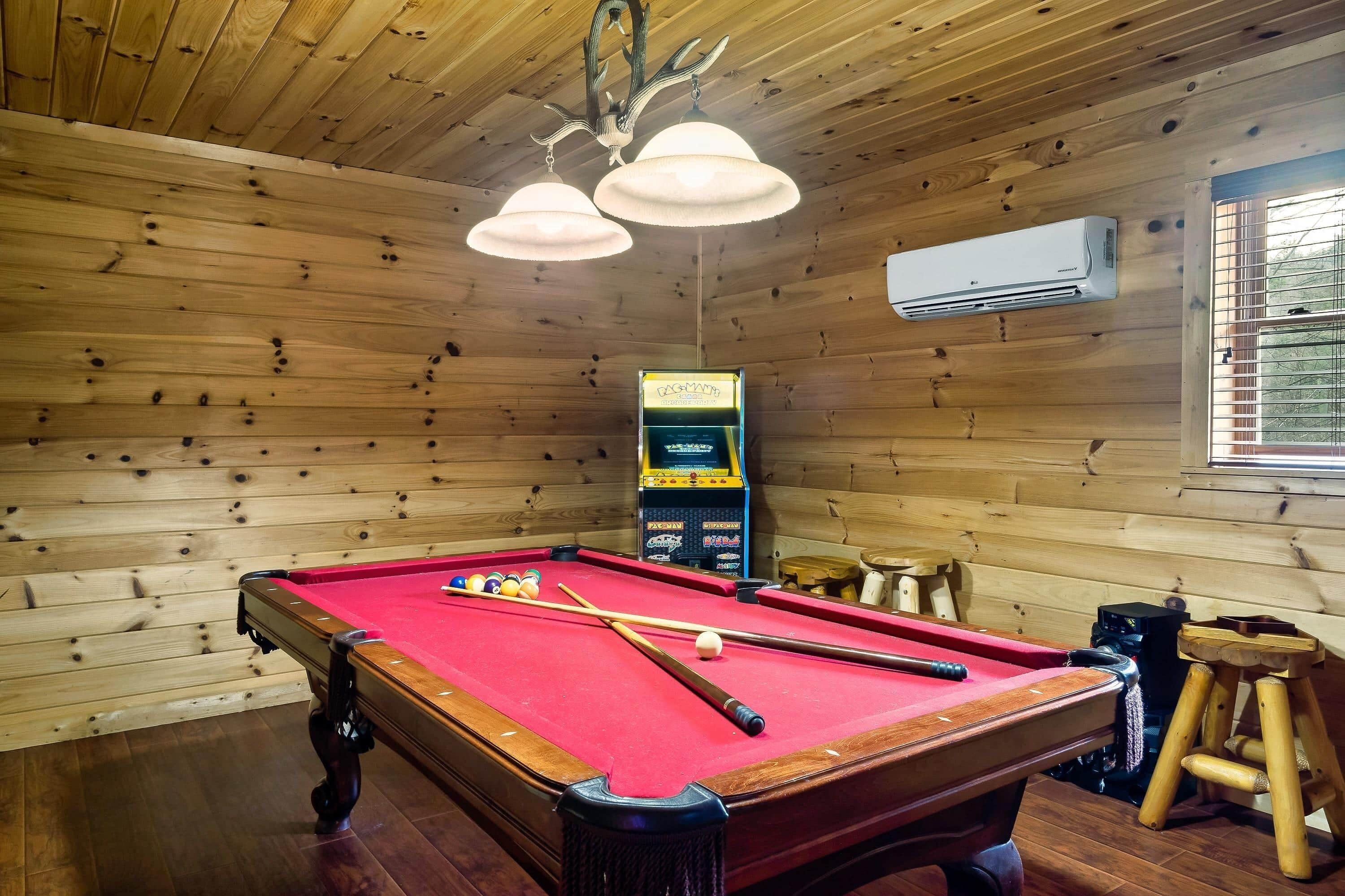 Une table de billard avec des billes et des queues, un plafond en bois et un panneau indiquant que la table de billard est à louer.