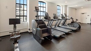 Een sportschool met loopbanden, elliptische trainers en een hometrainer.