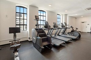 Ein Fitnessstudio mit Laufbändern, Crosstrainern und einem Ergometer.