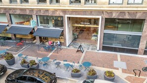 Een restaurant met terras, een winkel met een bord en een geparkeerde auto.