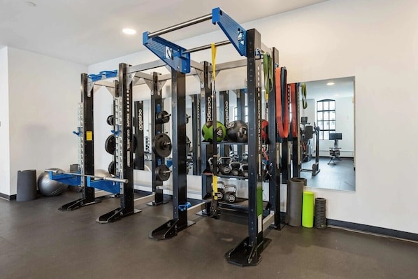 A gym with weightlifting equipment, exercise balls, and kettlebells.