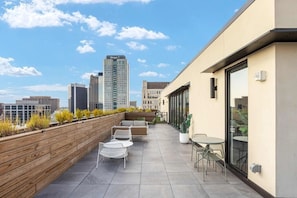 A rooftop terrace with outdoor seating, a wooden deck, and a city skyline view.