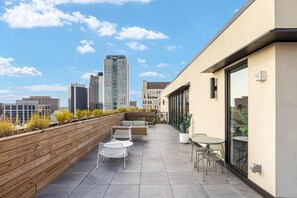 A rooftop terrace with outdoor seating, a wooden deck, and a city skyline in the background. - Downtown loft near theatres and the ballpark (Birmingham)