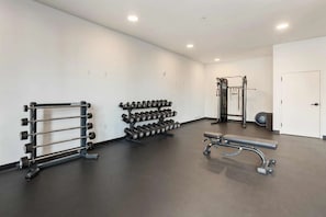 A gym with weightlifting equipment, a bench, and a door. - Downtown loft near theatres and the ballpark (Birmingham)