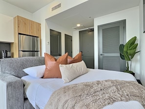 A modern bedroom with a grey sofa, a large bed with a fluffy blanket, and a potted plant. - Downtown loft near theatres and the ballpark (Birmingham)
