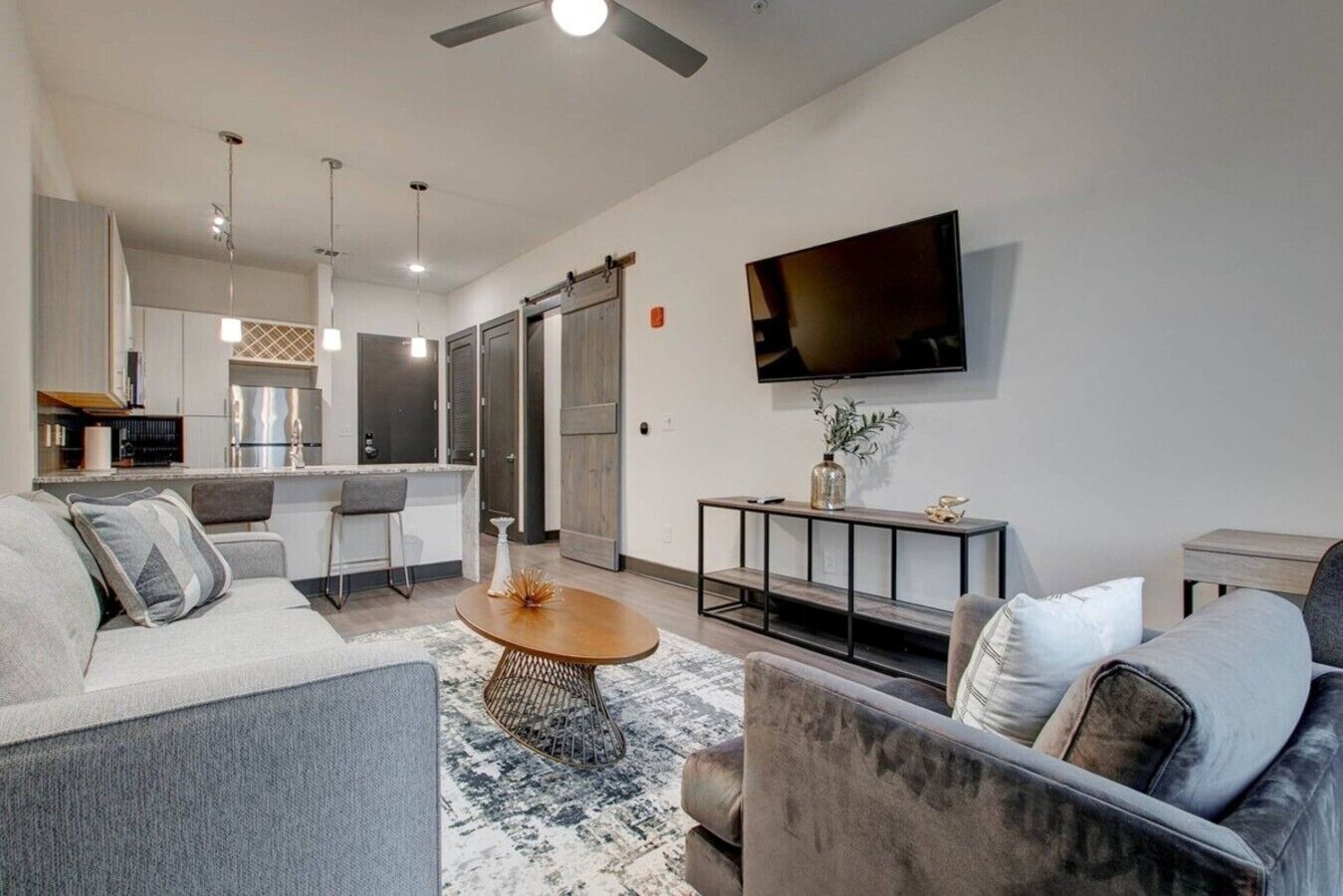 A modern living room with a sofa, coffee table, and a flat-screen TV mounted on the wall.