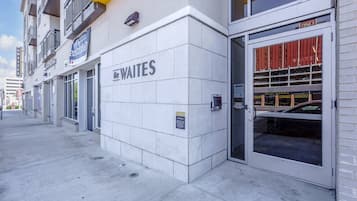 A building with a sign for 'The Waites' on the facade, a parking garage entrance, and a fire hydrant on the sidewalk.