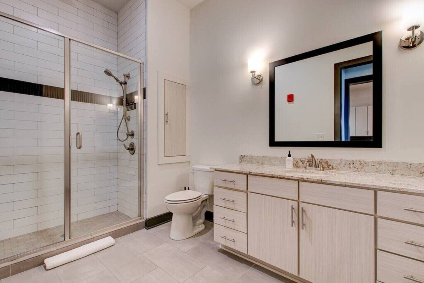 Une salle de bain moderne avec une douche à parois de verre, des toilettes et un meuble-lavabo avec un miroir.