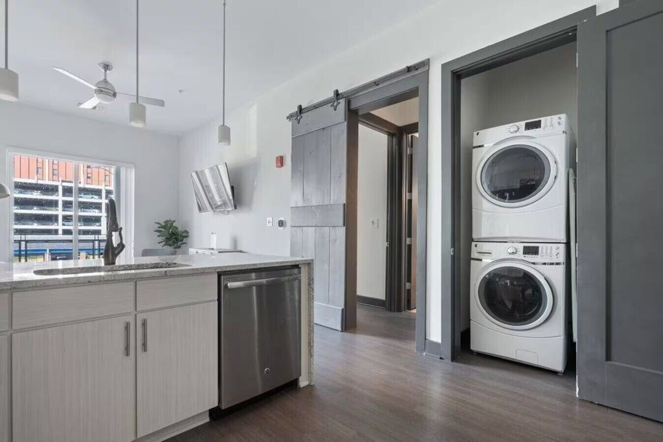 Une cuisine moderne équipée d’un lave-vaisselle, d’un lave-linge à deux tambours et d’une porte coulissante de style rustique.