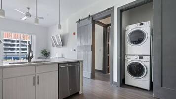 Une cuisine moderne équipée d’un lave-vaisselle, d’un lave-linge à deux tambours et d’une porte coulissante de style rustique.