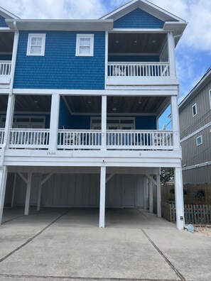 A two-story building with a balcony on the second floor, a covered front porch, and a garage. - 6 BR Townhome in Carolina Beach with Public Beach Access across the Street! (Carolina Beach)