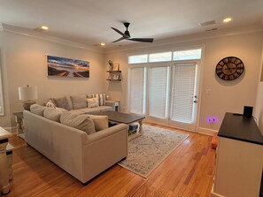 A living room with a sofa, coffee table, and a painting on the wall. - 6 BR Townhome in Carolina Beach with Public Beach Access across the Street! (Carolina Beach)