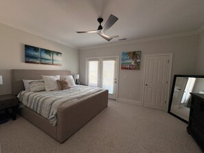 A bedroom with a bed, a ceiling fan, two doors, and artwork on the walls. - 6 BR Townhome in Carolina Beach with Public Beach Access across the Street! (Carolina Beach)