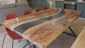Une table à manger moderne au design original, avec un motif de veinage du bois unique, accompagnée de chaises rouges.