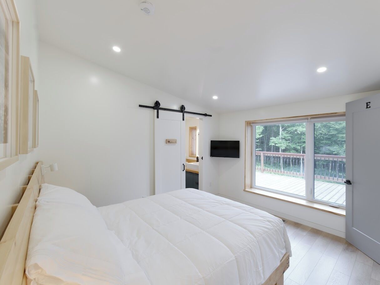 A bedroom with a bed, a window, and a door.