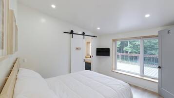 A bedroom with a bed, a window, and a door.