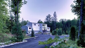 Un bâtiment à deux étages avec une allée et une zone boisée.