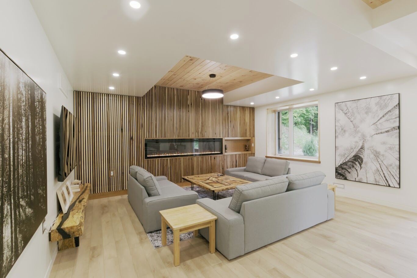 Un salon moderne avec un canapé gris, une table basse et une cheminée.