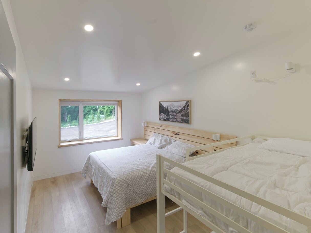 Une chambre avec deux lits, une fenêtre et un tableau au mur.