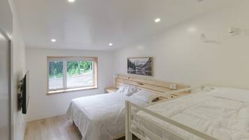 Une chambre avec deux lits, une fenêtre et un tableau au mur.