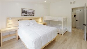 Une chambre à coucher avec un lit en bois, une table de chevet, un lit superposé et une armoire.