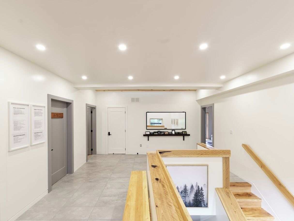 A hallway with a staircase, a mounted television, and informational posters on the walls.