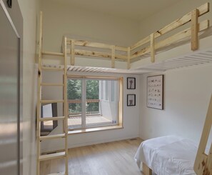 Ein Zimmer mit einem Etagenbett, einem Fenster mit Blick und einer Wand mit gerahmten Bildern.