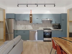 Eine moderne Küche mit integrierten Geräten, ein Essbereich mit einem Holztisch und eine eingebaute Sitzecke.