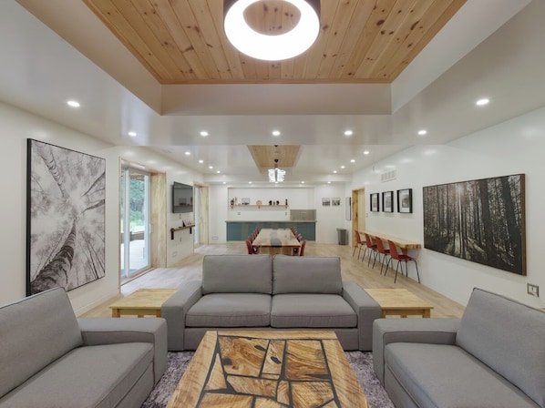 Un intérieur moderne avec un espace salon central, une table à manger et des œuvres d’art accrochées aux murs.
