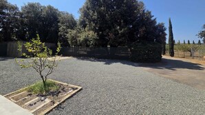 Ein Kiesparkplatz mit einem kleinen Baum und einem Zaun im Hintergrund.