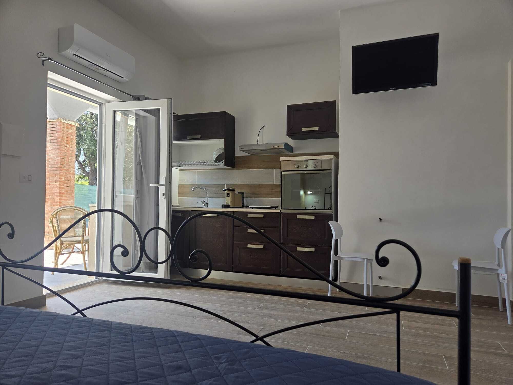 Un dormitorio con cama, una kitchenette con estufa y un televisor en la pared.