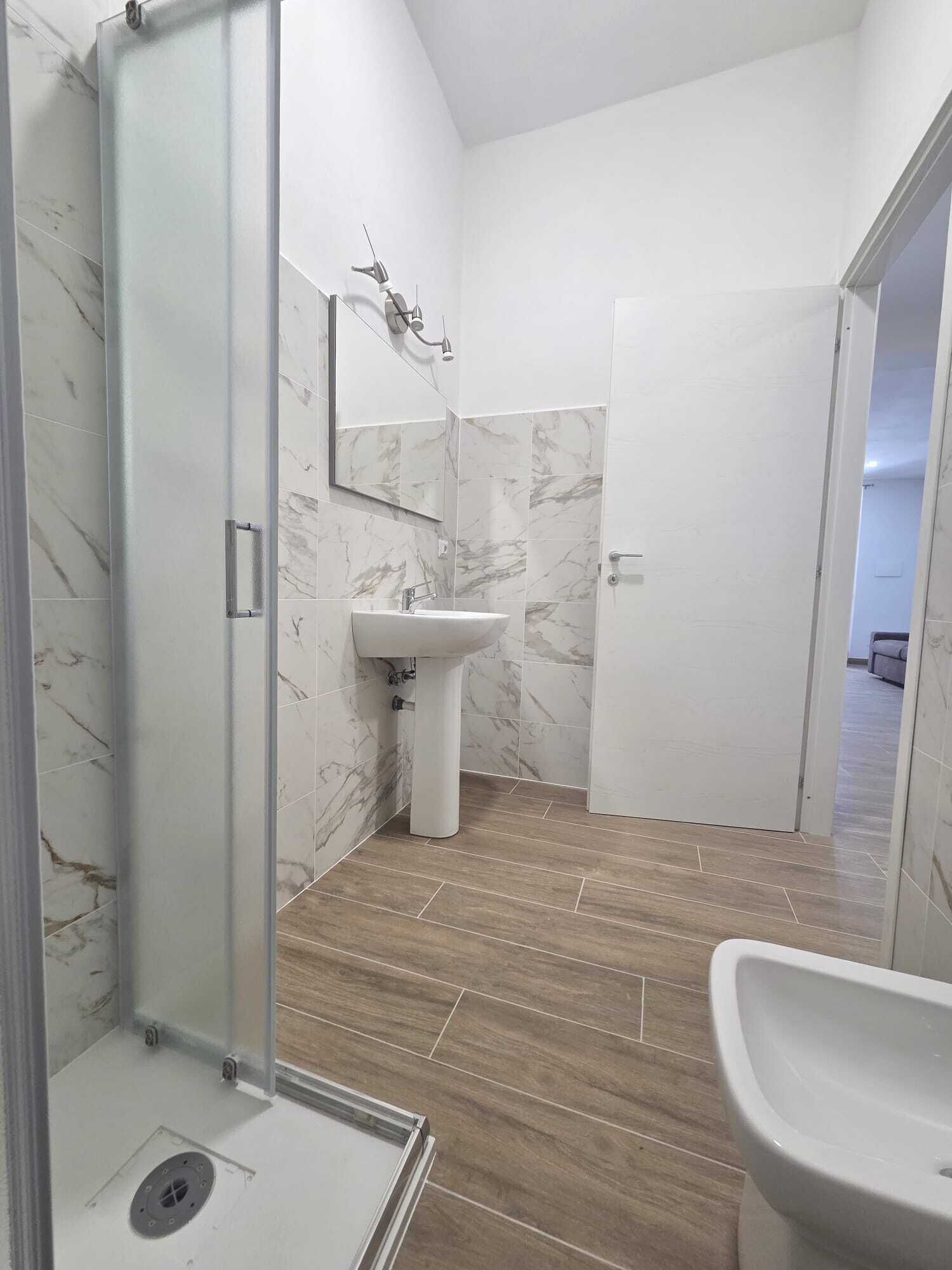 A modern bathroom with a glass shower enclosure, a sink, and a mirror.