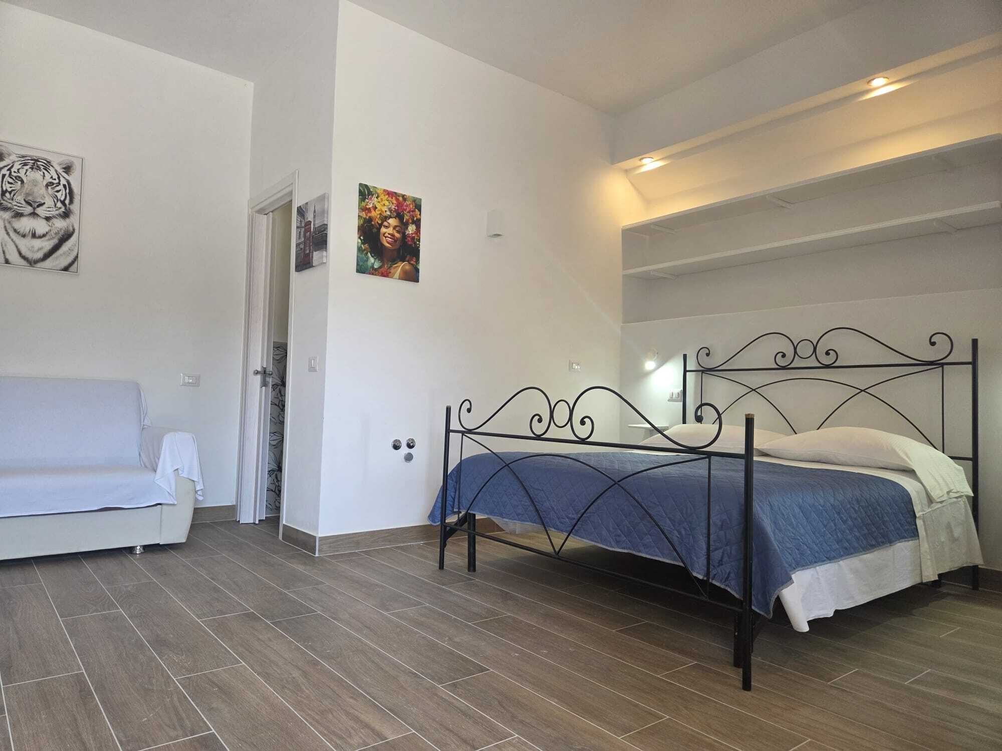 Une chambre à coucher avec un lit, un canapé blanc et une porte qui donne sur une autre pièce.