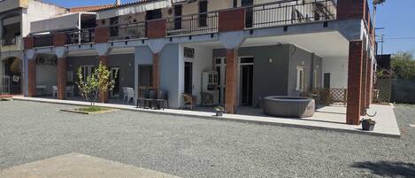 A two-story building with a balcony, outdoor seating, and a gravel driveway.