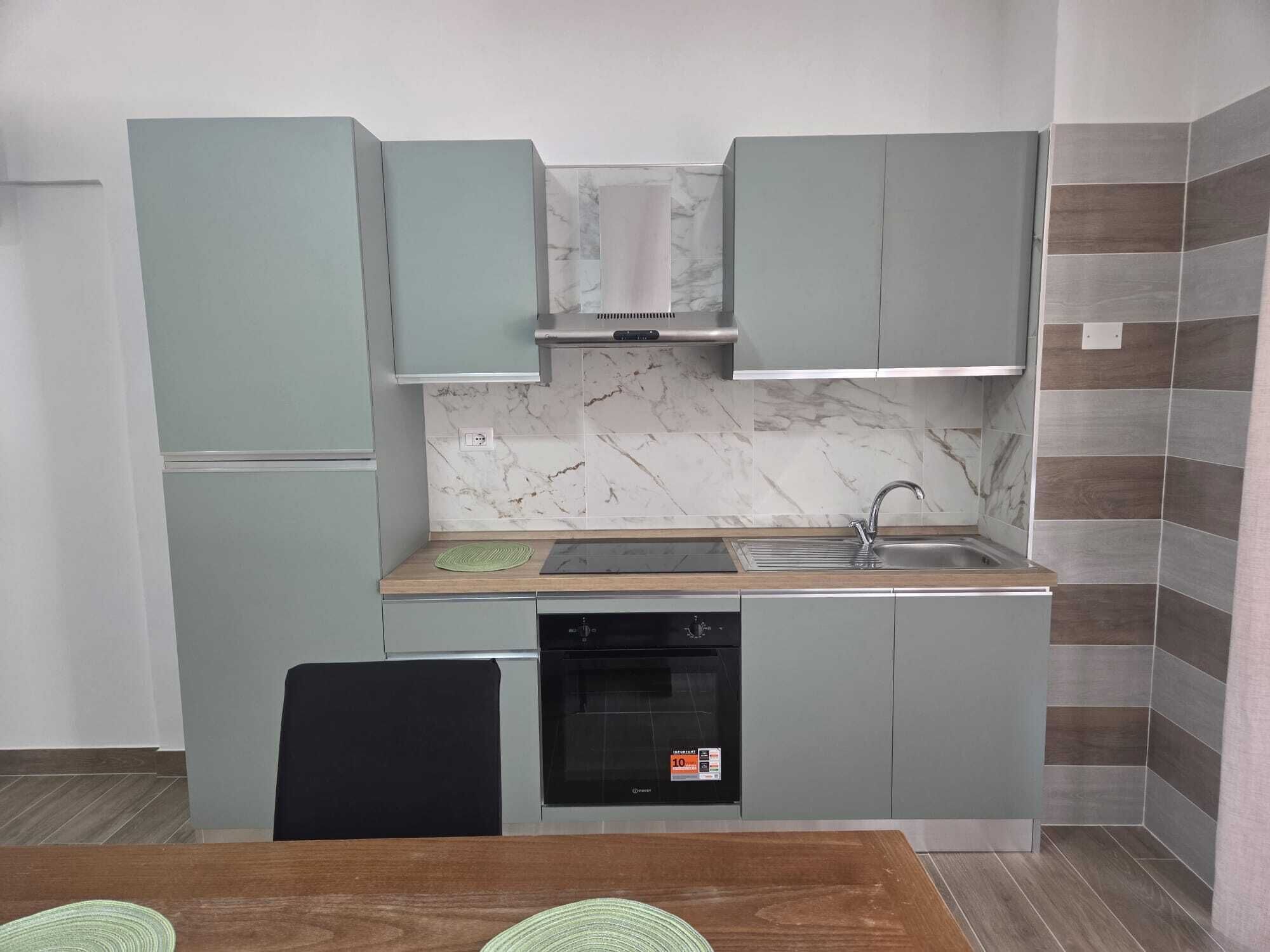 A compact kitchen with grey cabinets, a built-in oven, and a sink.