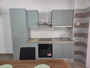 A compact kitchen with grey cabinets, a built-in oven, and a sink.