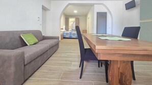 Ein modernes Wohnzimmer mit einer Couch, einem Holzesstisch und einer Küche im Hintergrund.
