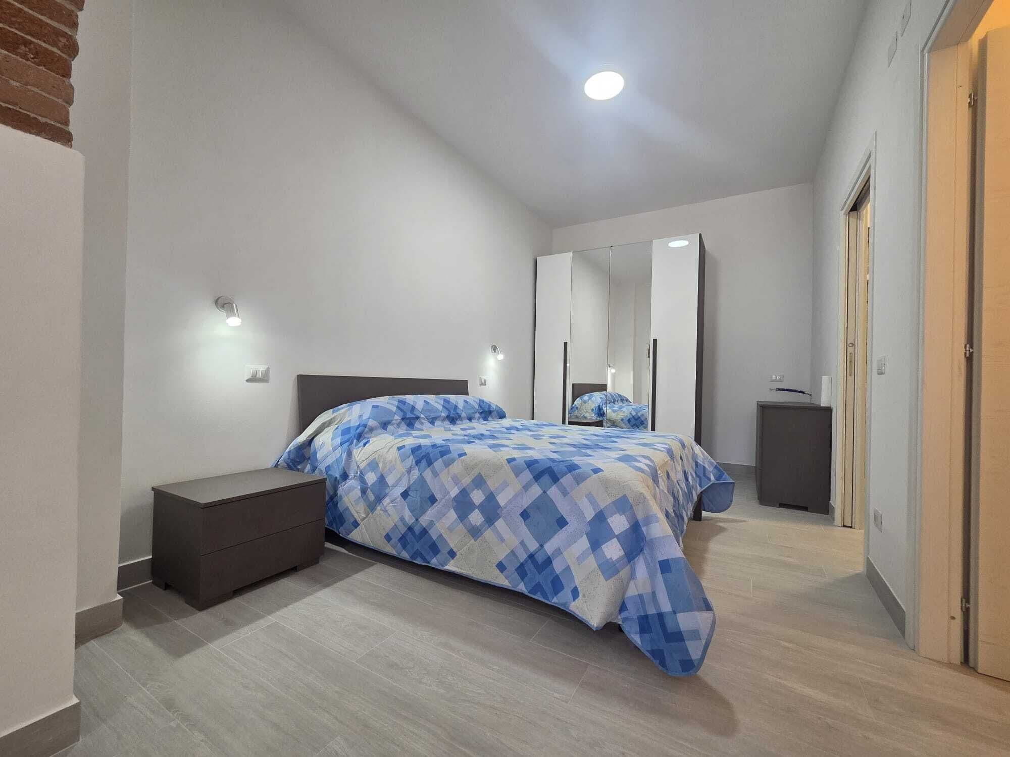 Une chambre à coucher avec un lit, des tables de chevet, une armoire et un miroir.