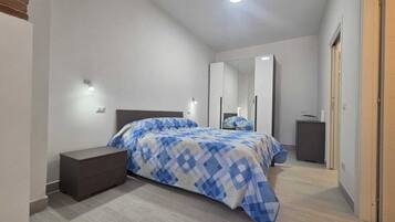 Une chambre à coucher avec un lit, des tables de chevet, une armoire et un miroir.