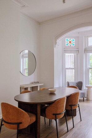 Ein Essbereich mit einem runden Tisch, sechs Stühlen, einem Spiegel und einem Fenster mit Blick.