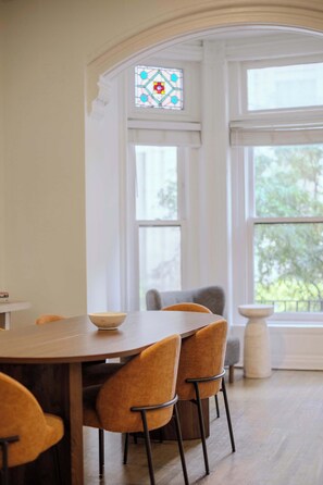 A dining area with a round table, four chairs, and a stained glass window. - Designer Loft 3E | Heart of Gold Coast/River North (Chicago)