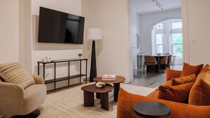 Ein modernes Wohnzimmer mit einer Couch, einem Couchtisch und einem an der Wand befestigten Flachbildfernseher.